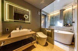 Un baño moderno con un espejo grande, un lavabo, un inodoro y una bañera.