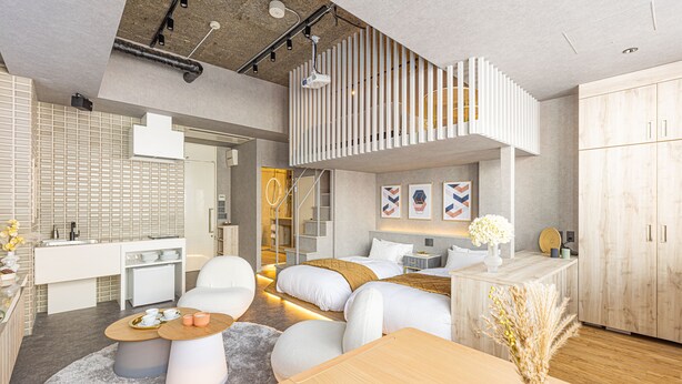 Una habitación moderna y bien iluminada con una cama de altillo, una zona de comedor y una cocina.