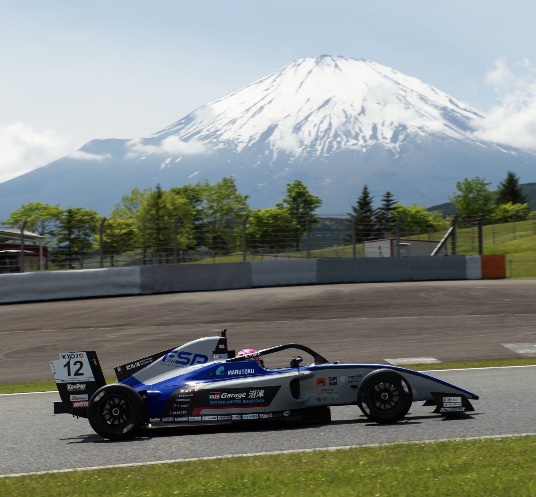 A race car on a track with a snow-capped mountain in the background.