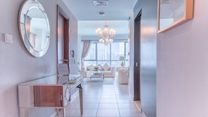 A modern hotel hallway with a round mirror, a wooden console table, a white sofa, a coffee table, and a chandelier. - Elite Royal Apartment - Burj Khalifa & Fountain view - Opal (Dubai)