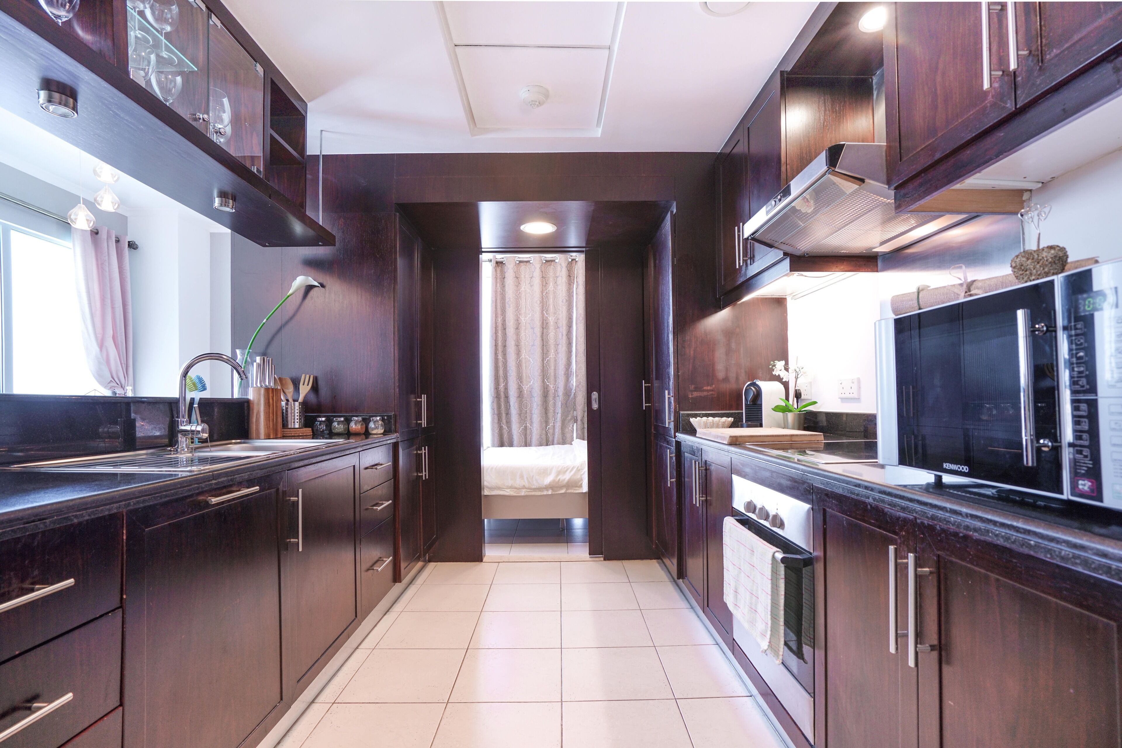 A modern kitchen with dark wood cabinets, a stainless steel sink, and a microwave.