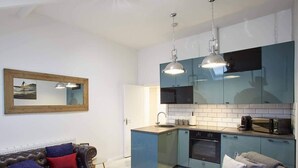 A compact living space with a kitchenette, a sofa, and a chair.