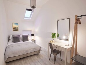Une chambre à coucher avec un lit, un bureau, une chaise et une lucarne.