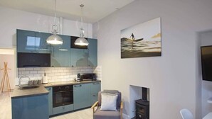 A modern kitchen with blue cabinets, a central island, and a fireplace.