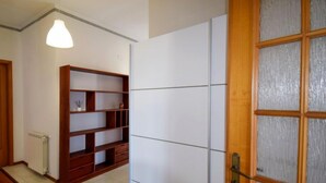 Een kamer met een houten boekenkast, een radiator en een schuifdeur met geëtste glaspanelen.