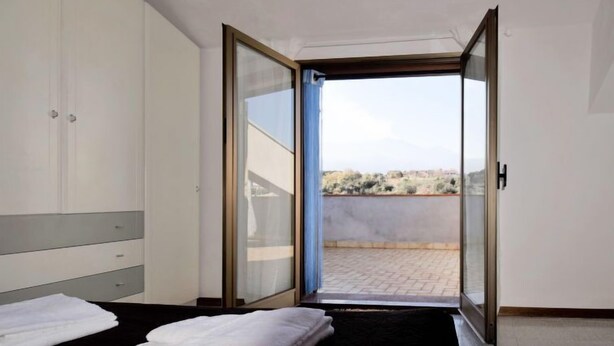 Een slaapkamer met een bed, een kledingkast en een schuifdeur naar een balkon.