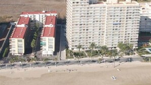 A high-rise hotel with multiple floors, a beach in the foreground, and palm trees. - Les Doyes Bl 3 1-36  LEK (Peñiscola)