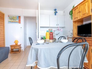 A dining area with a table set for two, a television on a wooden cabinet, and a map on the wall. - Apartment 3 Mats by Interhome (Canet-Plage)