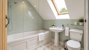 Une salle de bain avec un puits de lumière, une baignoire, un lavabo et des toilettes.