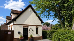 A two-story building with a sloped roof, a front door, and a small porch area. - Measure Cottage - Sleeps up to 4 - Henley in Arden - HOT TUB (Henley-in-Arden)