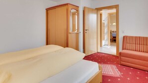A bedroom with a bed, a wooden wardrobe, a red carpet, and a sofa. - Quaint Apartment in Hainzenberg near Horbergbahn (Hainzenberg)