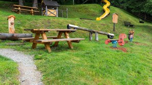 A playground with a seesaw, a slide, and a wooden bench. - Quaint Apartment in Hainzenberg near Horbergbahn (Hainzenberg)