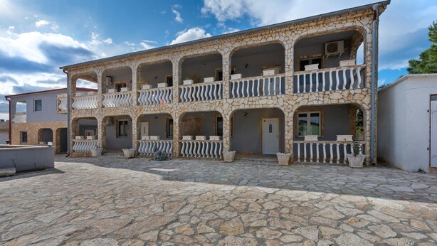 A two-story building with a stone facade and multiple balconies. - Simplistic Apartment in Vir With Garden (Vir)