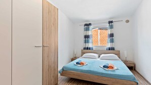 A compact room with a bed, wooden wardrobe, and a window with curtains. - Simplistic Apartment in Vir With Garden (Vir)