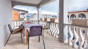 A balcony with a table and chairs, overlooking a cityscape with buildings and mountains. - Simplistic Apartment in Vir With Garden (Vir)