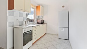 A compact kitchen with a built-in oven, a microwave, and a refrigerator. - Simplistic Apartment in Vir With Garden (Vir)
