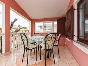 Eine überdachte Terrasse mit Tisch, Stühlen und Geländer, mit Blick ins Freie.