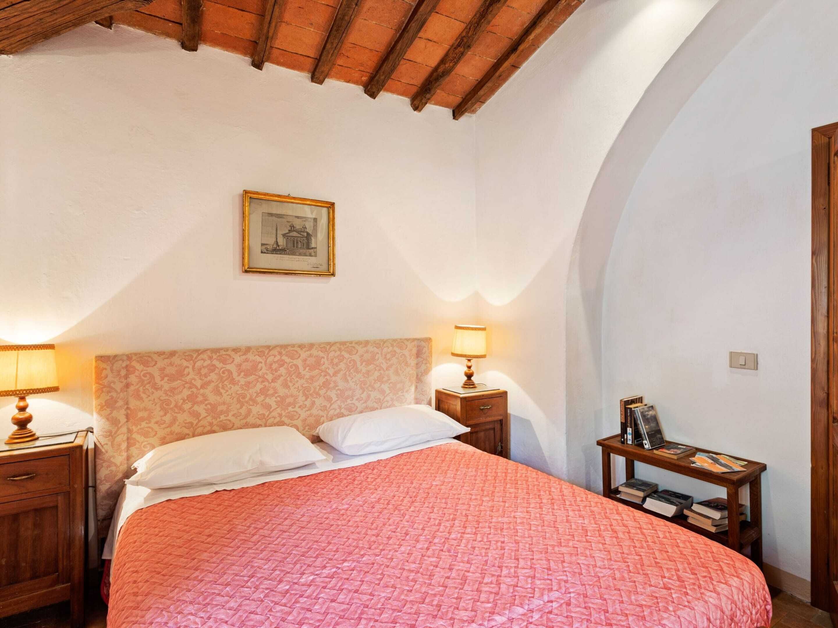 Une chambre à coucher comprenant un lit, deux tables de chevet, une commode, un tableau encadré accroché au mur et une porte en bois.