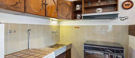 A kitchen with wooden cabinets, a washing machine, a stove, and tiled walls.