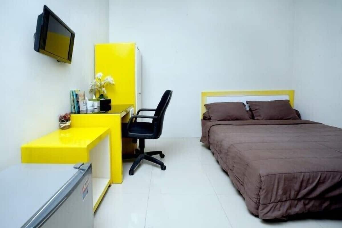 A bedroom with a bed, a desk, a chair, and a television.