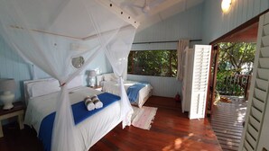 Un dormitorio con dos camas, ventilador de techo y ventana con vistas al exterior.