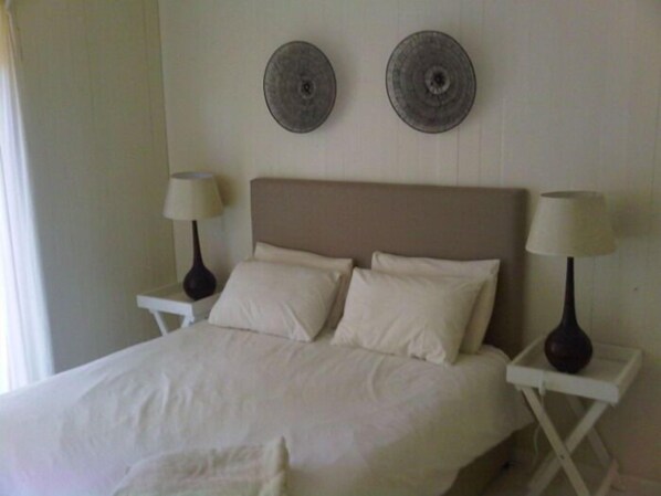 A neatly made bed with two pillows and a white duvet, flanked by two bedside tables with lamps. - Mar Azul 14 (Ponta d'Ouro)