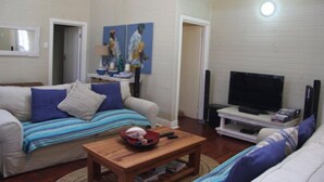 Ein Wohnzimmer mit einer Couch, einem Couchtisch, einem Fernseher und Kunstwerken an der Wand.