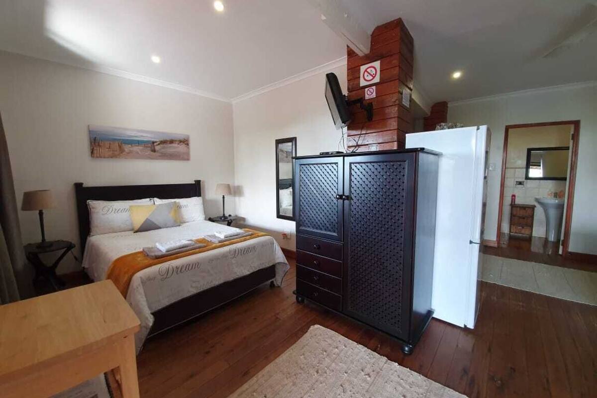 A bedroom with a bed, a wardrobe, a desk, and a mirror.