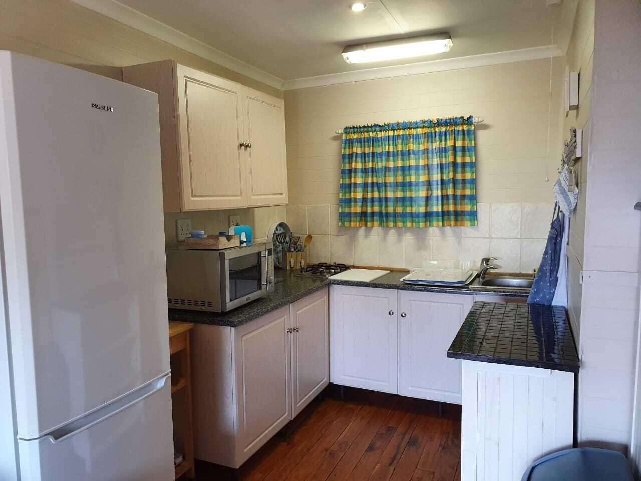 A compact kitchen with white cabinets, a microwave, a sink, and a refrigerator.
