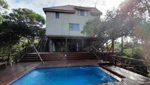A two-story house with a wooden deck and a swimming pool. - Mar Azul 18 (Ponta d'Ouro)