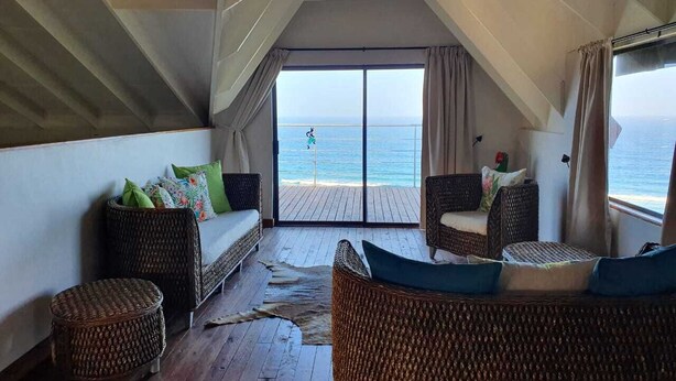 A cozy balcony with wicker furniture, a view of the sea, and a wooden floor. - Mar Azul 18 (Ponta d'Ouro)