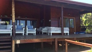 A wooden deck with several white chairs and a small table, likely a seating area for guests. - Mar Azul 1B (Ponta d'Ouro)