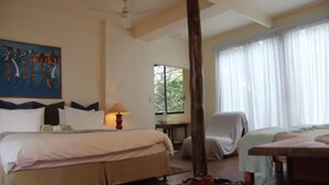 A hotel room with a large bed, a desk, a chair, and a window with curtains. - Mar Azul 26 (Ponta d'Ouro)