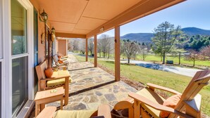A covered patio with stone flooring, wooden furniture, and a view of a mountainous landscape. - Resort Perks, Amazing Views: 3BR Sky Valley Home! (Sky Valley)