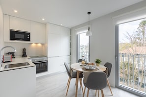 A modern kitchen with a built-in microwave, a sink, and a dining area with a table and chairs.
