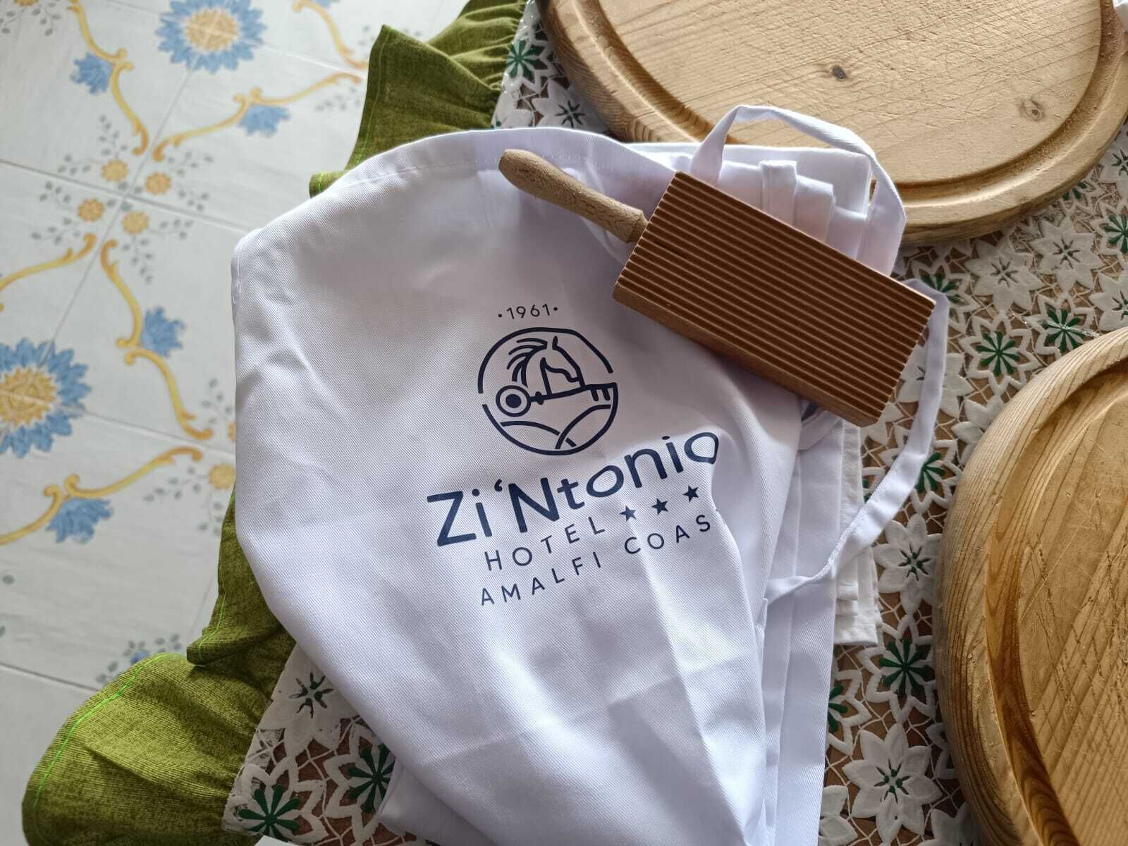 A white bag with the logo and name "Zi'Ntonio Hotel Amalfi Coas" and a wooden brush.