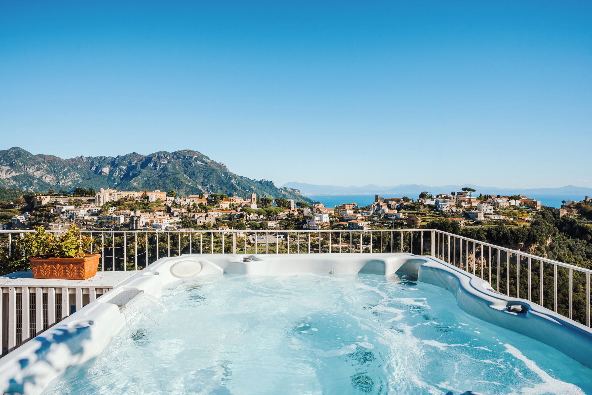 Un jacuzzi con vistas a un pueblo costero y montañas.