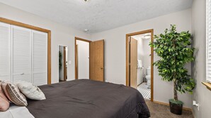 A bedroom with a large bed, a potted plant, and a closet with sliding doors. - Fenced Backyard | Near Mall & Hospitals (39) (Boise)