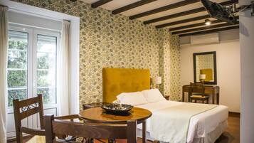 Habitación de hotel con cama, escritorio, silla, mesa con un tazón y ventana con cortinas.