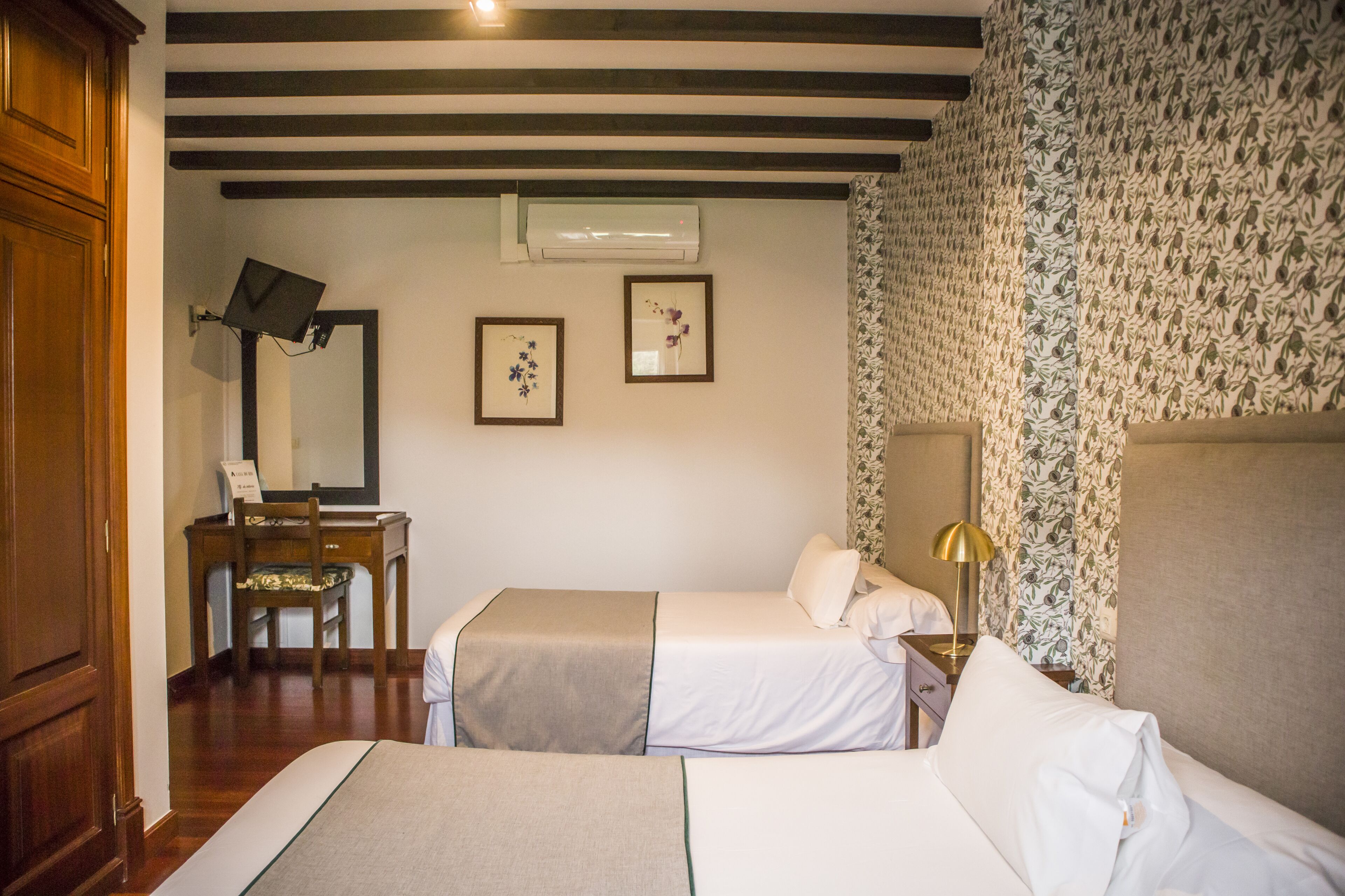 A hotel room with two beds, a desk, a chair, and a mirror.
