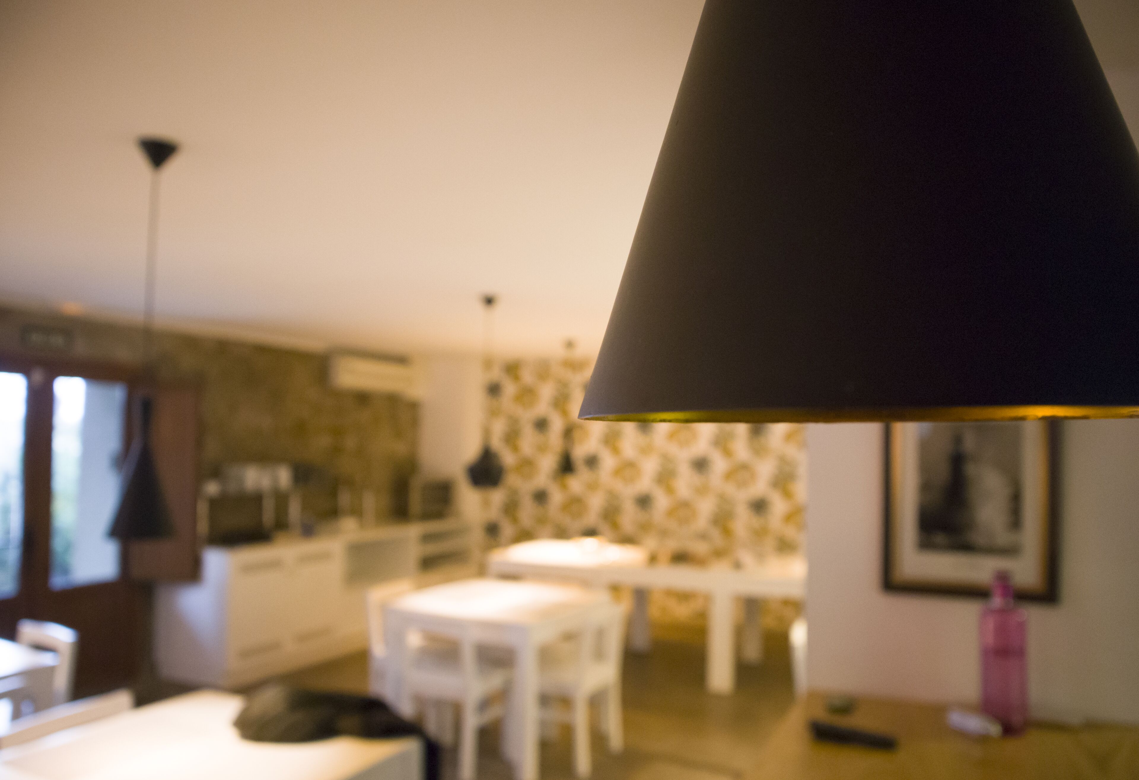 A blurred interior of a room with a dining table, chairs, and a hanging lamp.