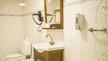 A bathroom with a bathtub, a sink, a mirror, a towel rack, and a toilet.