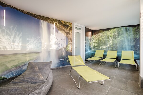 A modern waiting area with a large mural of a waterfall, a sofa, and several yellow chairs. - The Brucklyn Apartments (Erlangen)