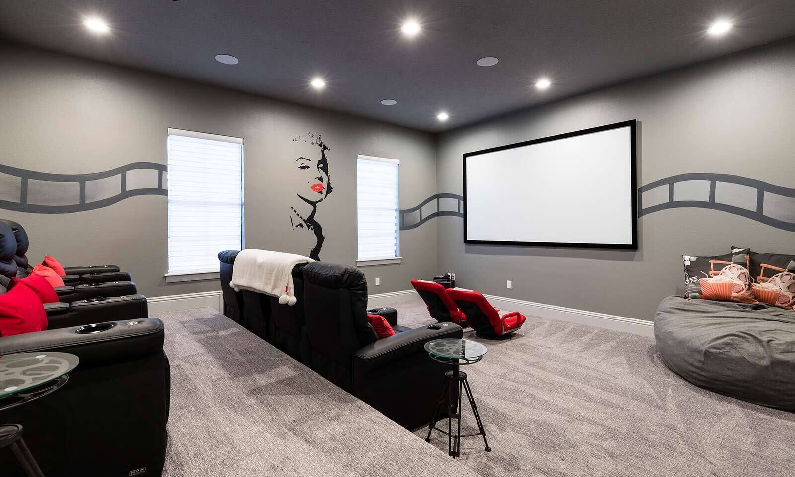 A home theater room with a large screen, reclining chairs, and a bean bag.
