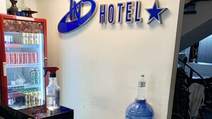 A hotel reception area with a refrigerator stocked with beverages, a large water dispenser, and a sign indicating the hotel name. - Bao Ngoc Hotel (Ho Chi Minh City)