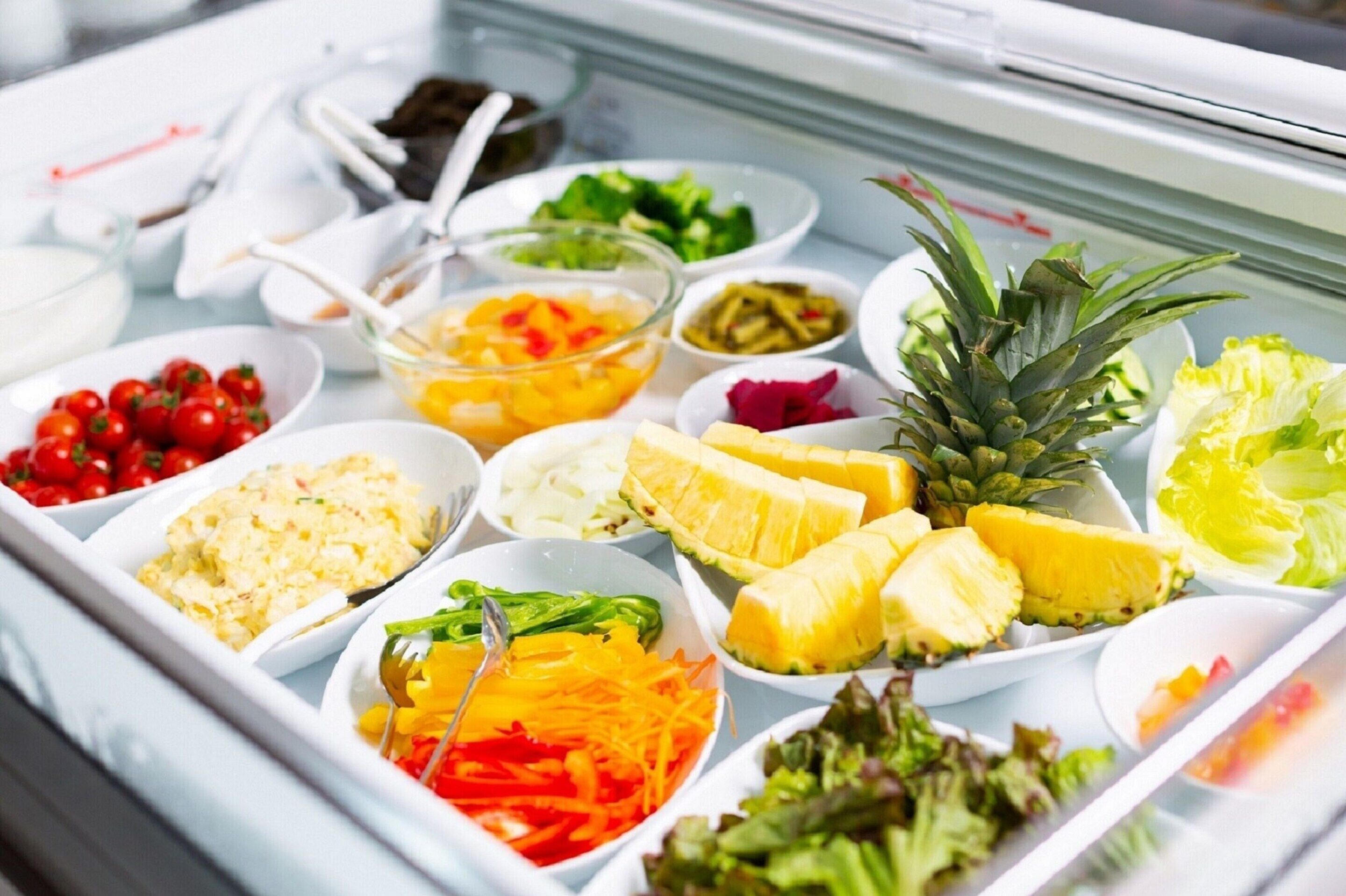 A buffet with various dishes including fruits, vegetables, and salads.