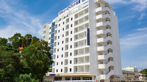 Un hotel de varios pisos con fachada blanca, múltiples balcones y un cielo despejado.