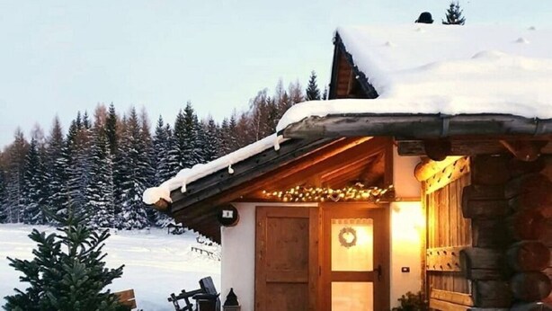Eine rustikale Holzhütte mit einer Holztür und einer Bank davor.