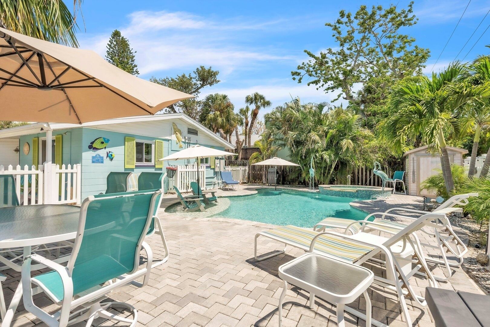 A pool area with lounge chairs, umbrellas, and a building with a fish mural.