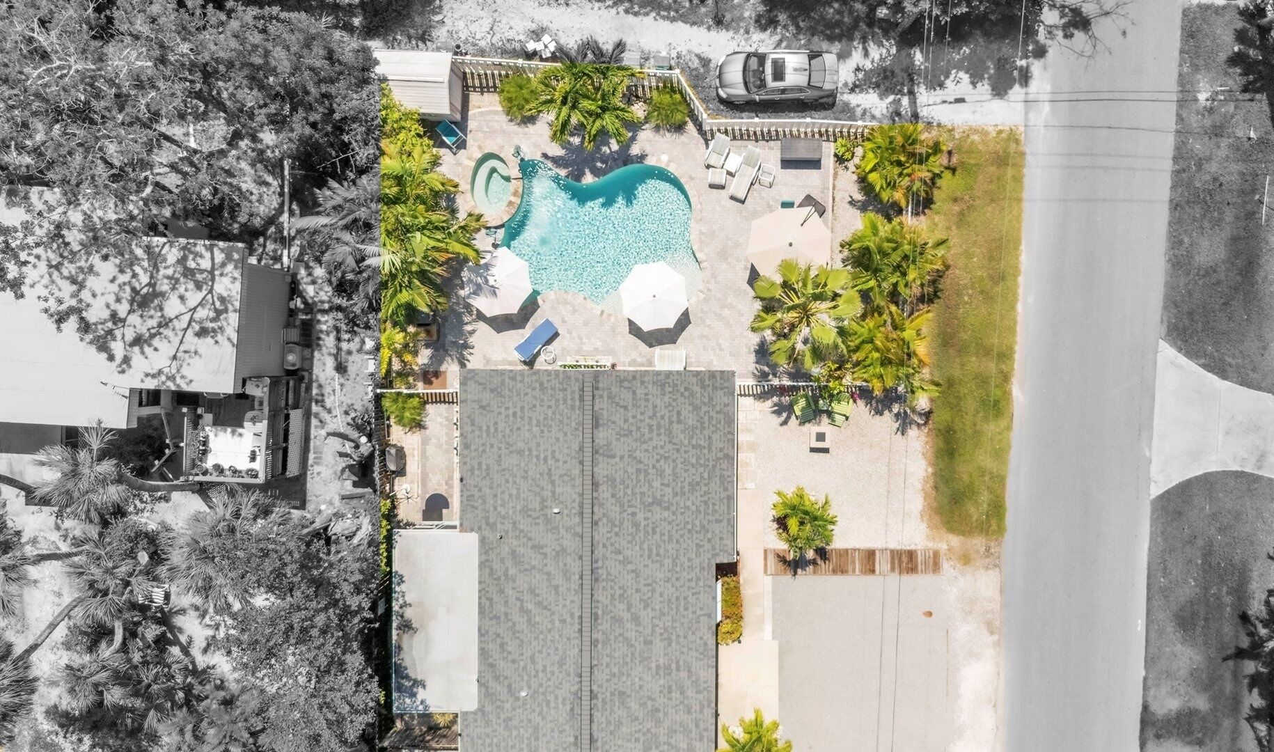 An aerial view of a residential property with a swimming pool, lounge chairs, and palm trees.